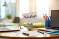 Ã¢â¬ÅVacationÃ¢â¬Â note on office desk. Laptop supplies, blurred background Royalty Free Stock Photo